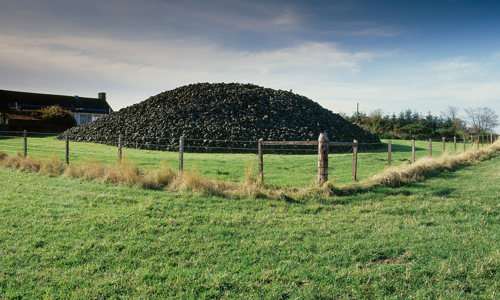 A round stone cairn on a grassy field