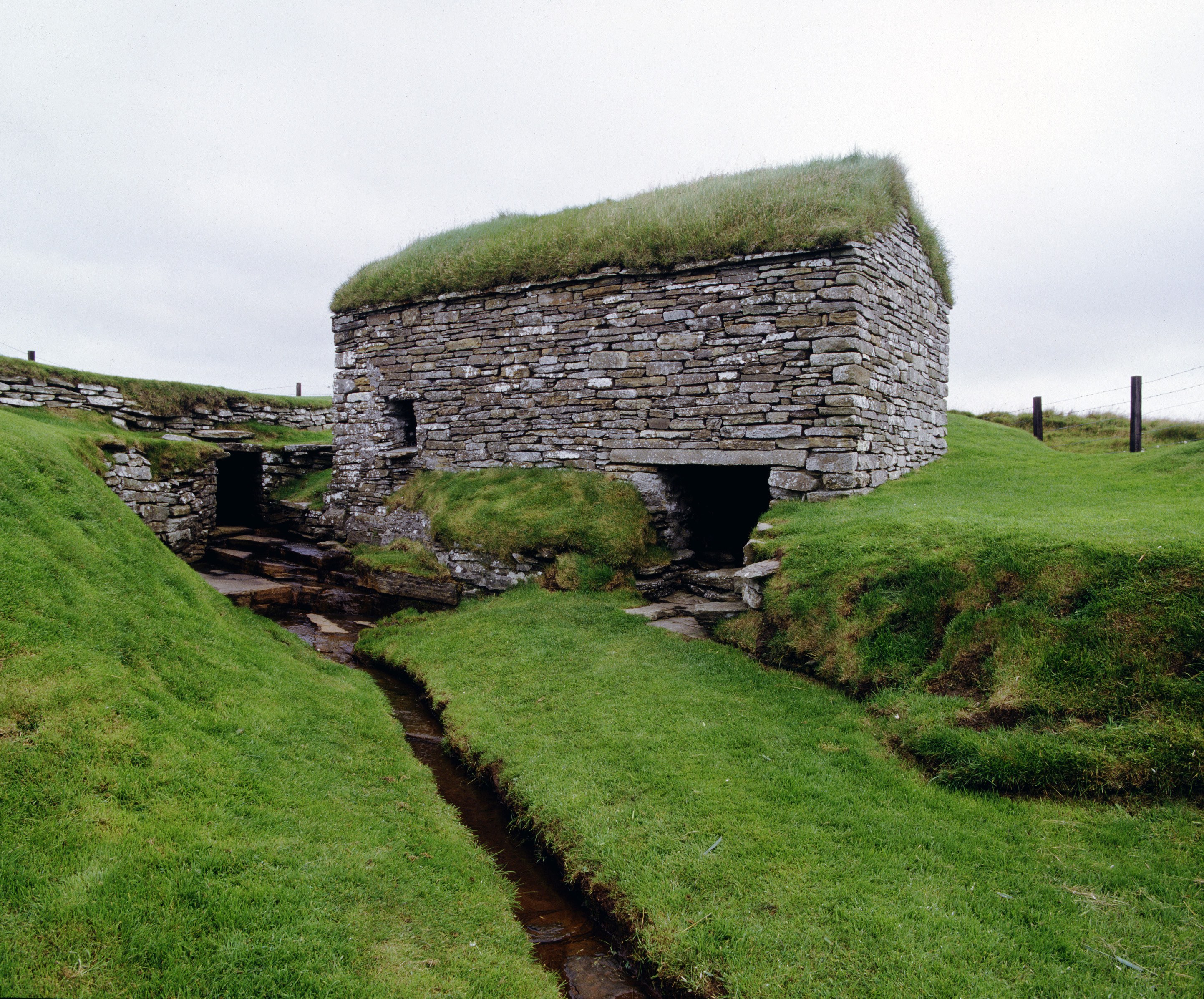 A small grass-covered house built over a small stream