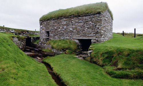 A small grass-covered house built over a small stream