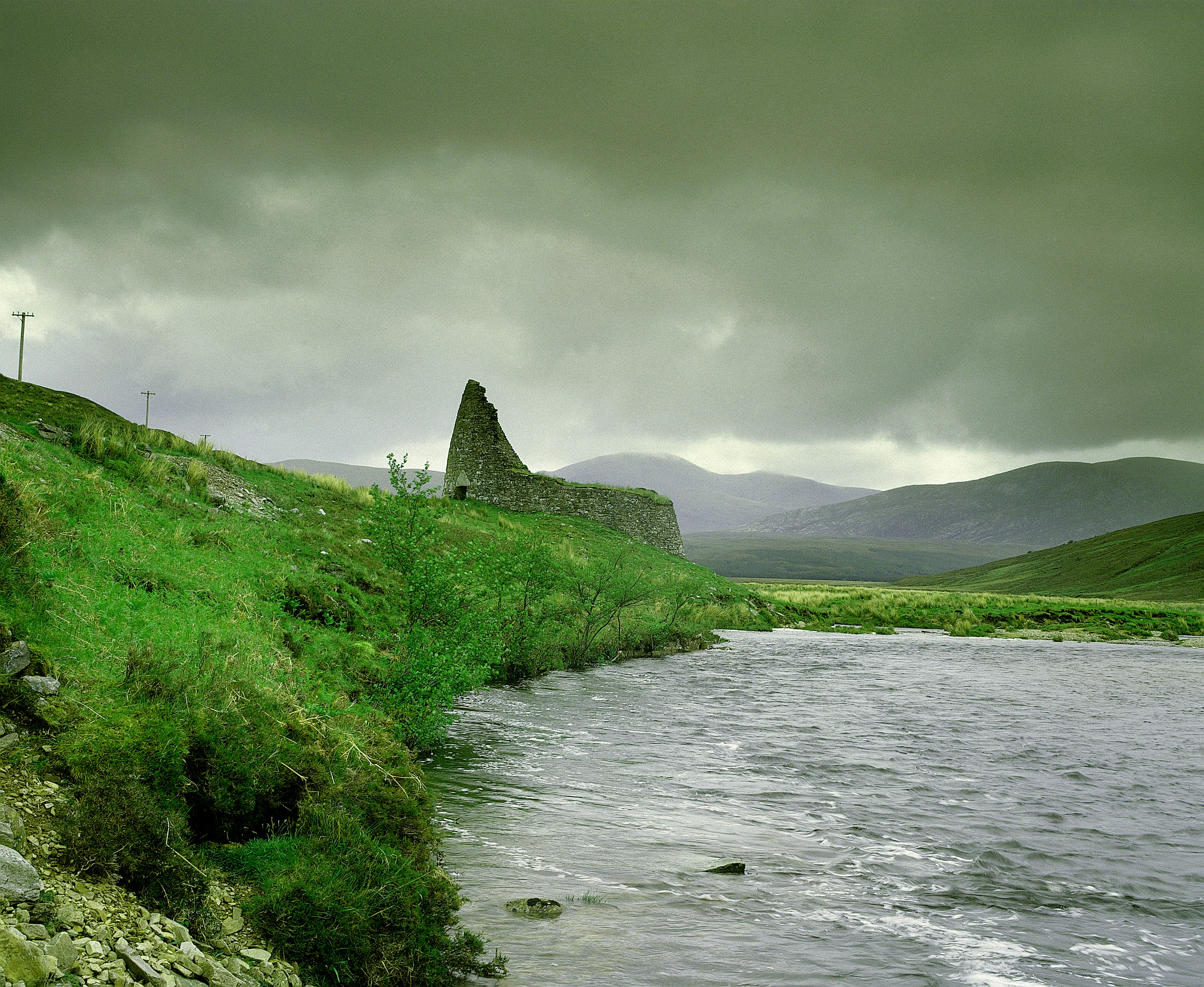 A picturesque Highland landscape with a ruined broch beside a stream