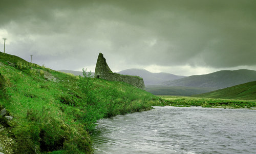 A picturesque Highland landscape with a ruined broch beside a stream