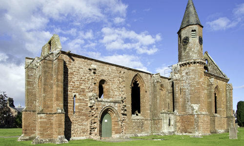 A red stone cathedral in good condition in front of a blue sky