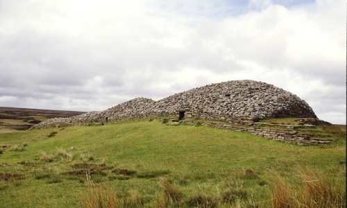 A well preserved stone cairn on a grassy landscape