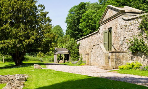 The foundations of Deer Abbey on the left, with a classic portico on the right that is the entrance to the site