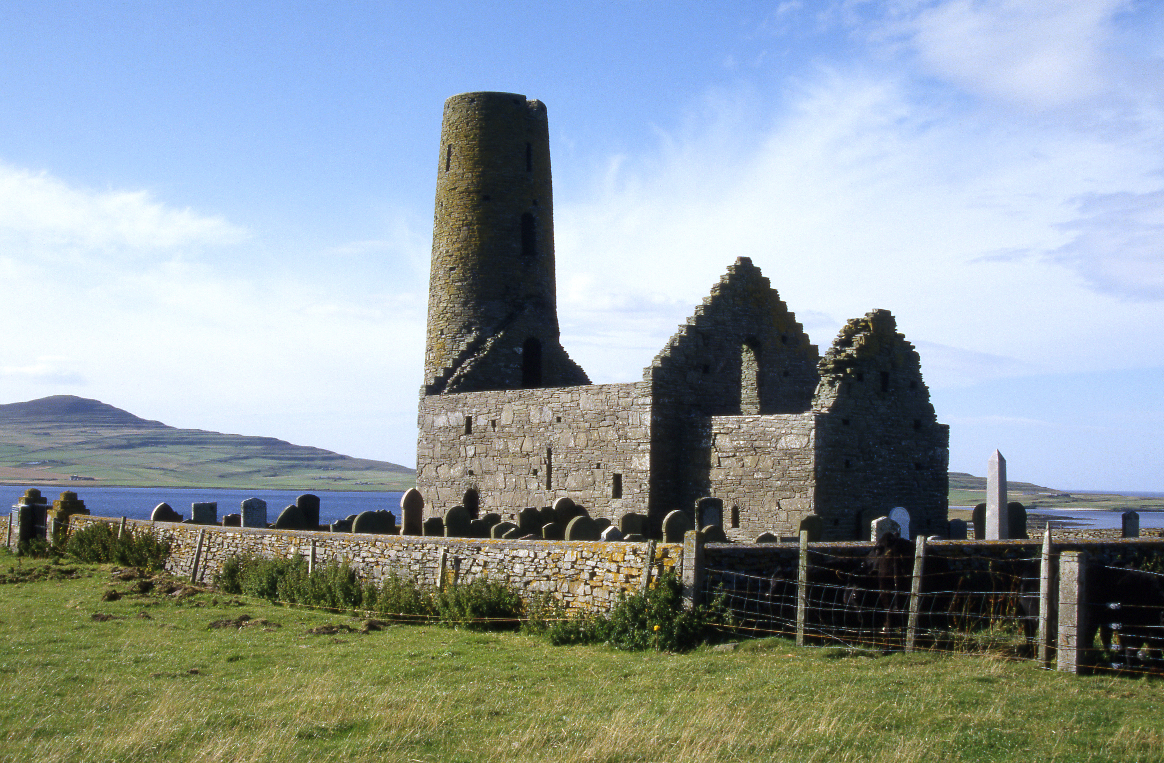 The complete but roofless ruin of St Magnus Church with a large round tower just behind it