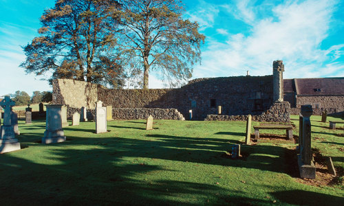 A small graveyard with a church ruin in the background