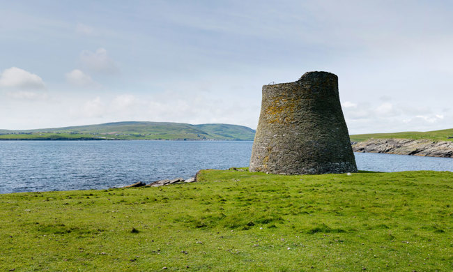 A tall, intact looking broch next to the sea