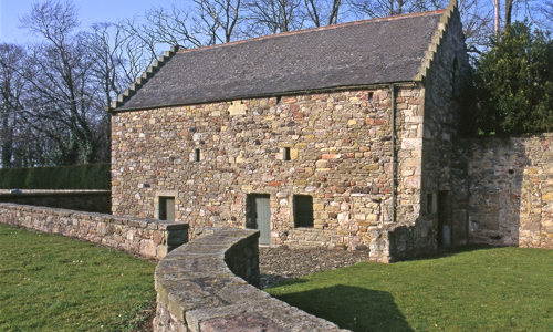 A two-storey stone barn surrounded by stone walls