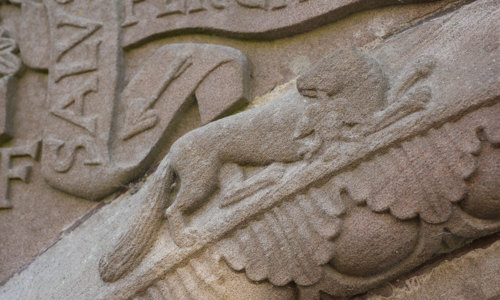 A stone carving showing a kind of animal, decorations and Latin writing