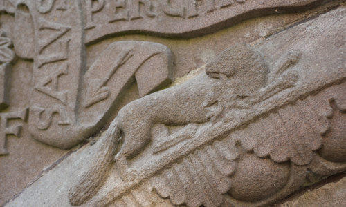 A stone carving showing a kind of animal, decorations and Latin writing