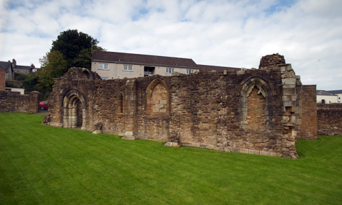 The ruins of Maybole Chapel in front of a modern housing development
