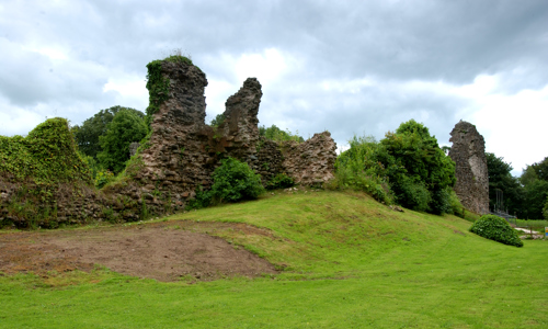 The overgrown ruins of Lochmaben Castle on a grassy hill