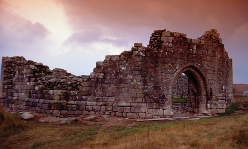 The ruined remains of Loch Doon Castle with a reddish sky
