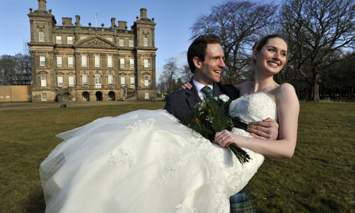 Duff House exterior with newlywed husband carrying wife, both smiling