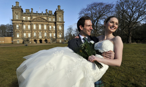 Duff House exterior with newlywed husband carrying wife, both smiling