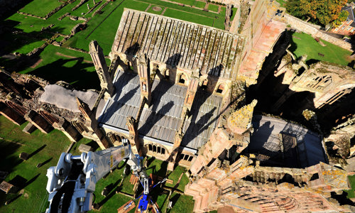 Staff members on a crane conducting an aerial survey of the roof of Melrose Abbey.