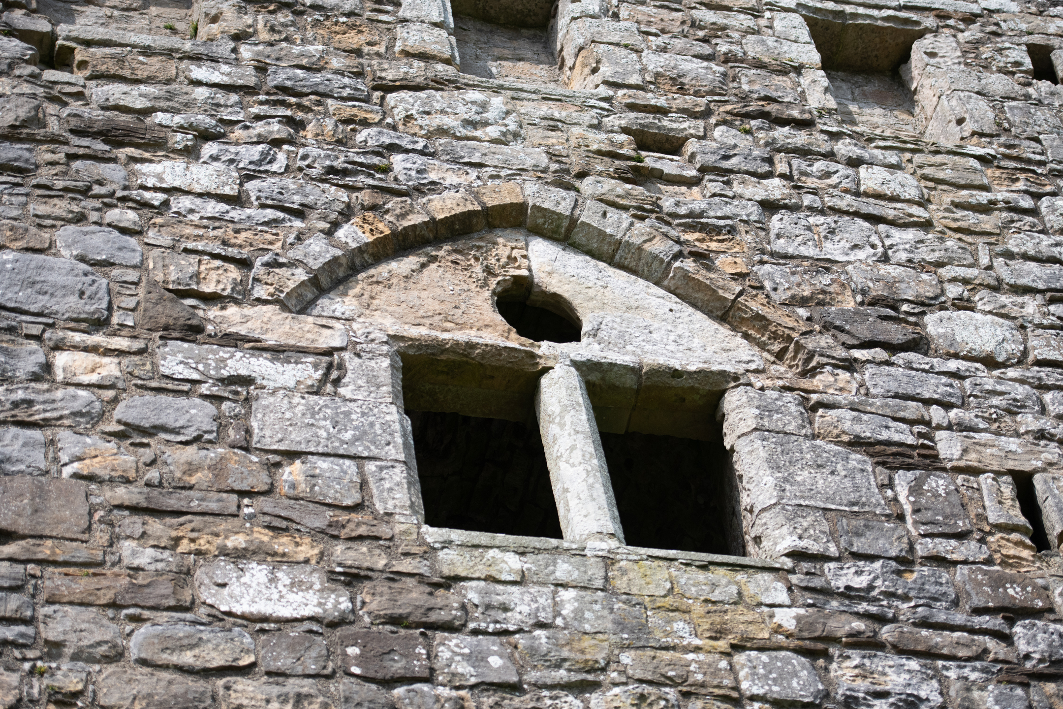 Close-up view of an arched stone window with twin pillars at Hermitage Castle