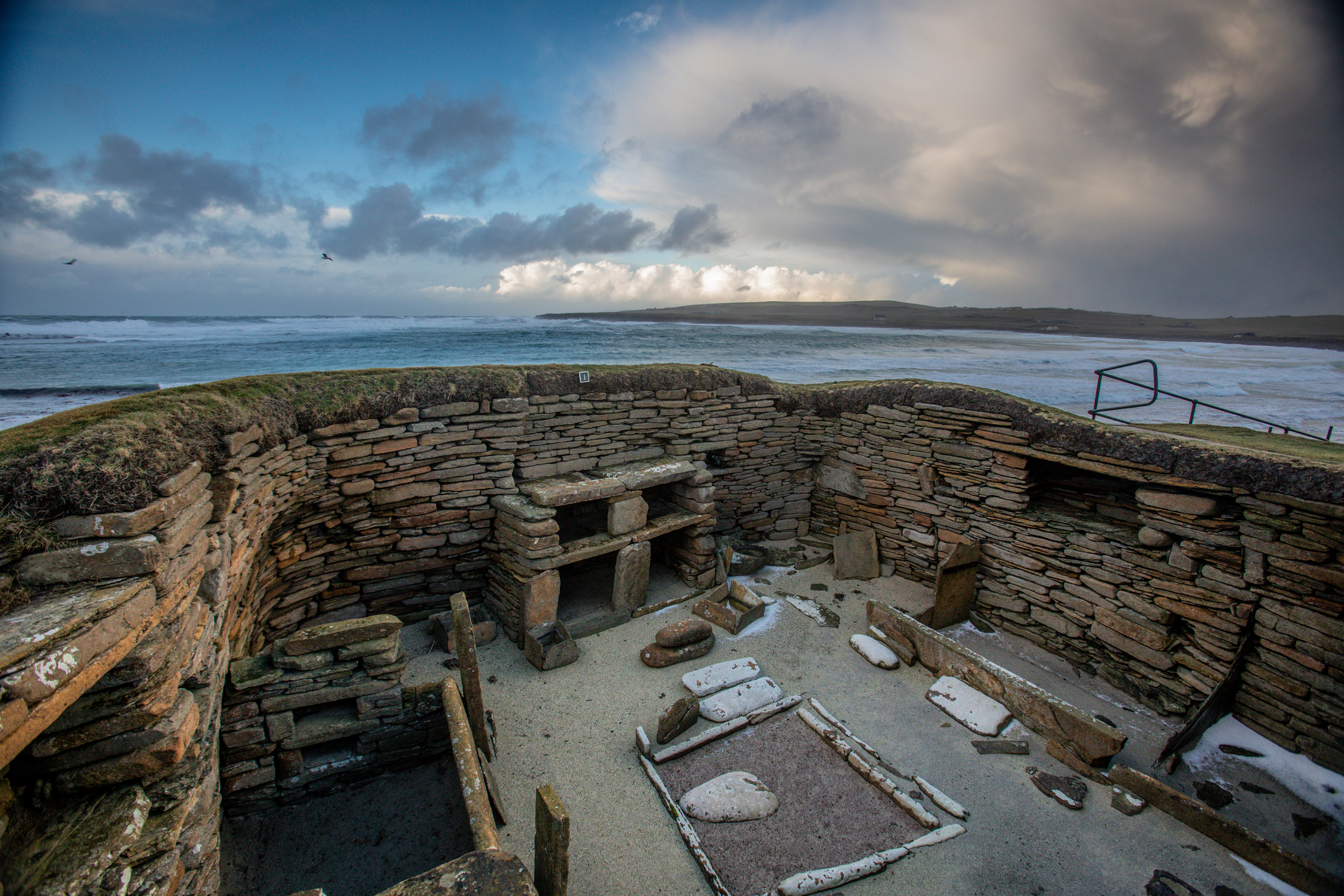 View inside Skara Brae against the backdrop of the sea on a stormy day