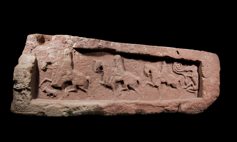 A photograph of a stone carved with three horsemen 