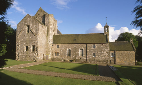 A photograph of a building that has been built in different phases, on a sunny day.