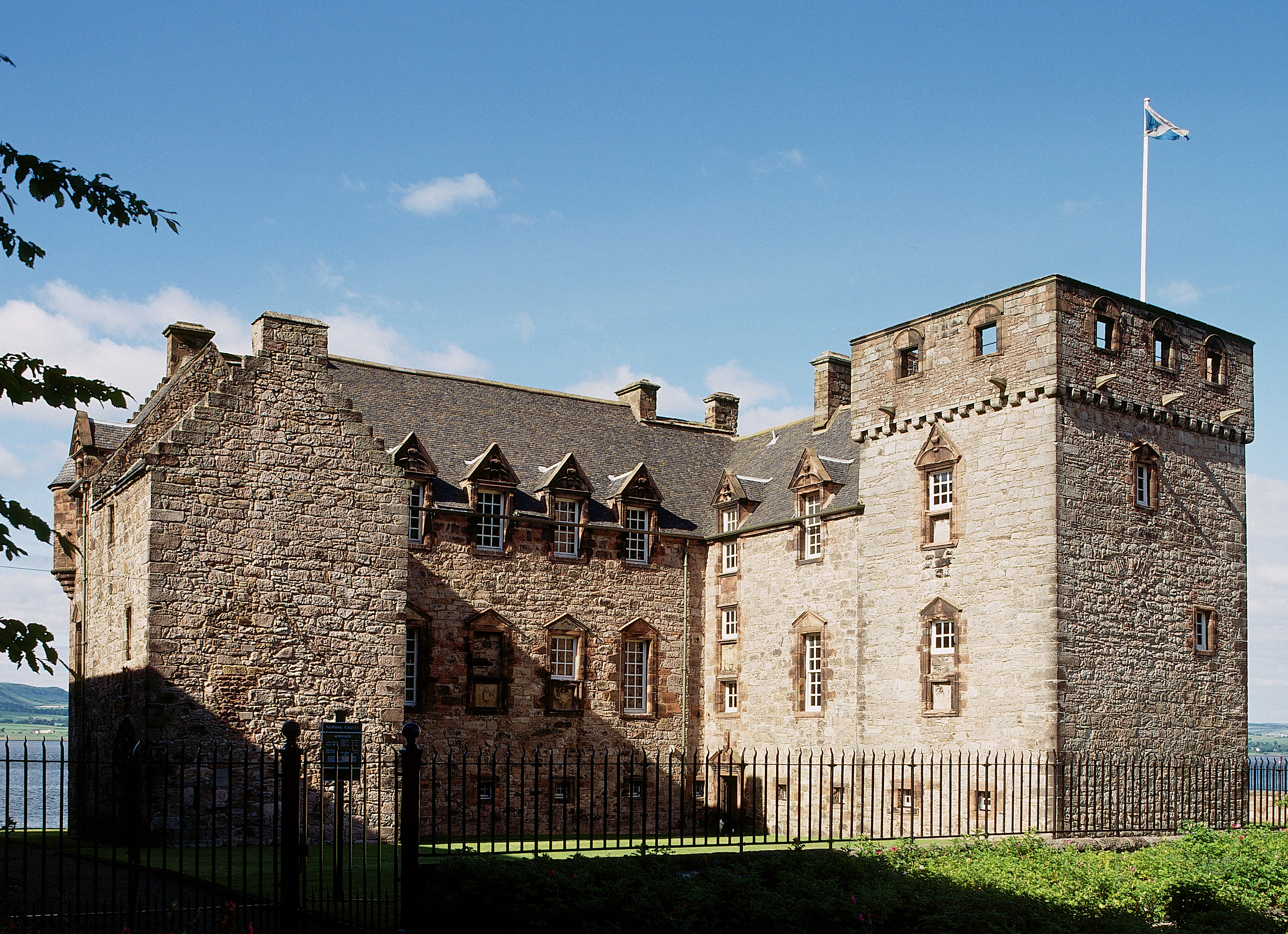 A photograph of a large house with a square tower, flying a Saltire flag.