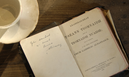 An old edition of a Gaelic-language novel open to its title page.