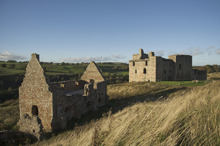 Outside daytime view of Crichton Castle and surrounding fields with blue sky