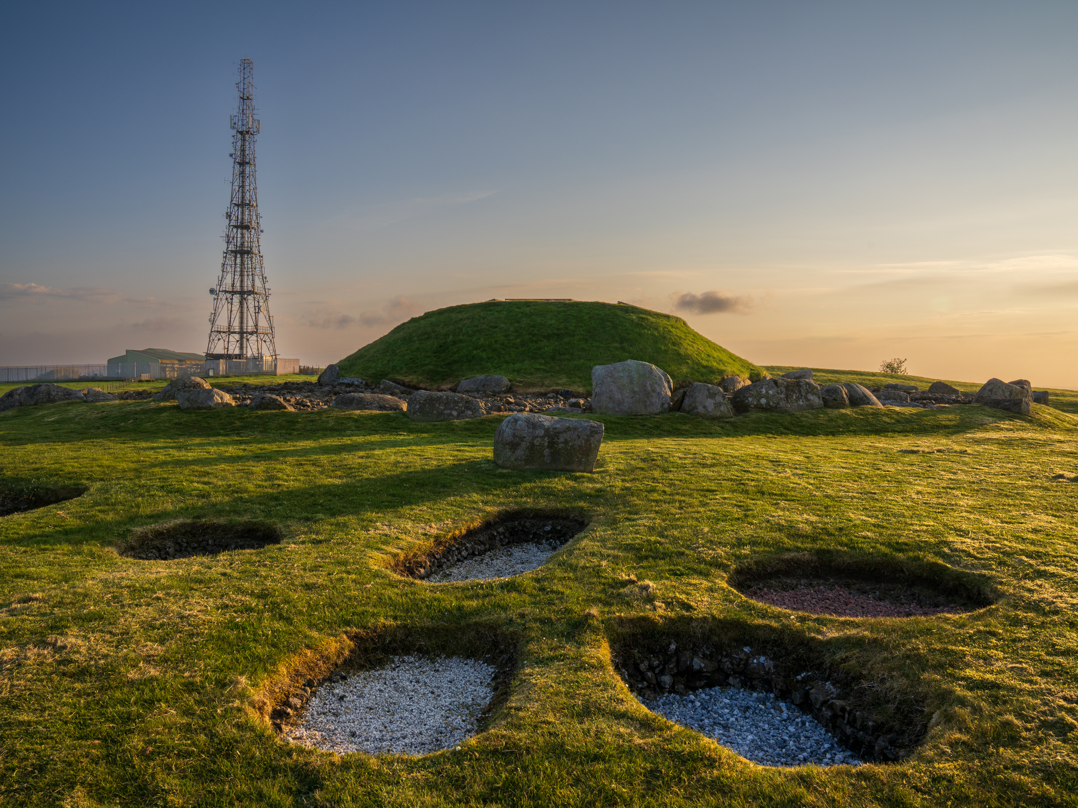 Small hill  in grassy area with holes in front of it and rocks