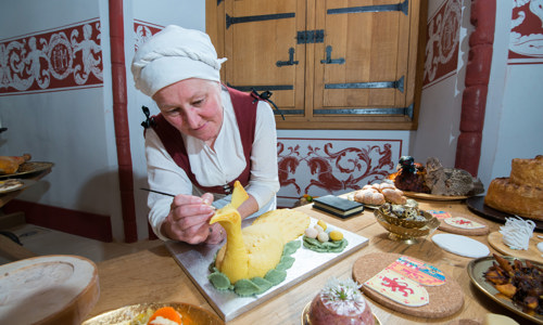 A re-enactor dressed as a kitchen worker works on preparing a feast at Stirling Castle.