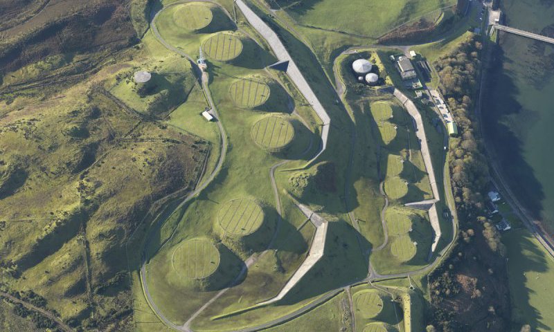 An aerial photograph depicting a series of round earthrworks on a shoreline.