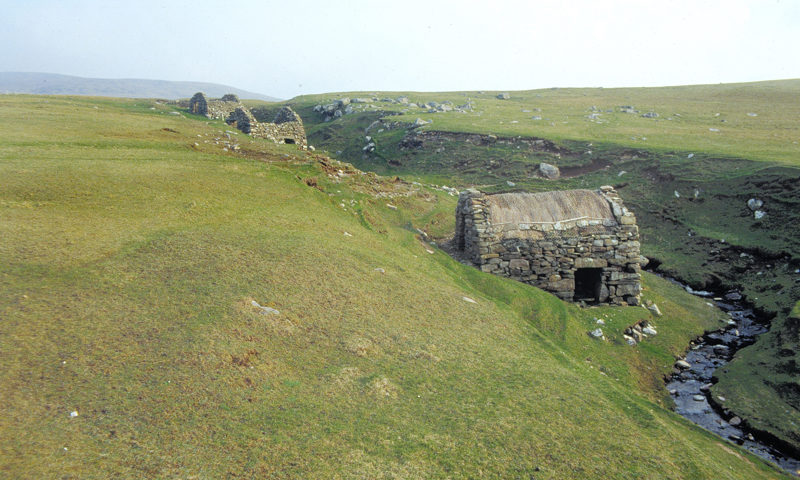 A row of historic stone houses next to a small stream.
