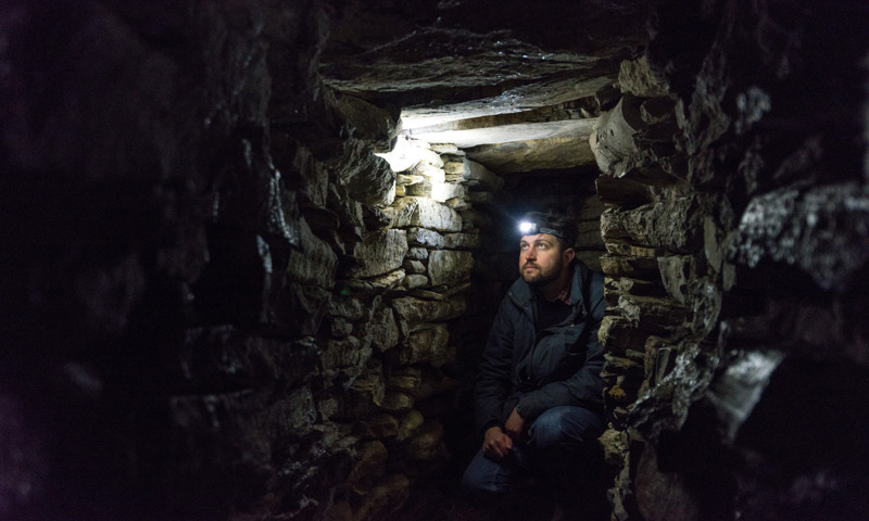 A staff member investigates the interior of the Broch of Gurness.
