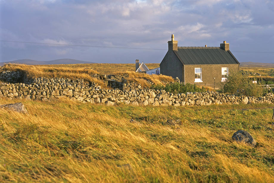 The Blackhouse, Arnol, next to a more modern building.