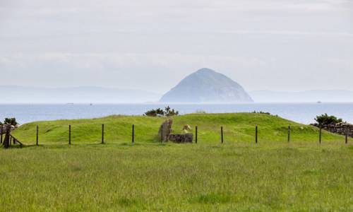General view of Torrylin neolithic chambered cairn on Arran with Ailsa Craig in the background