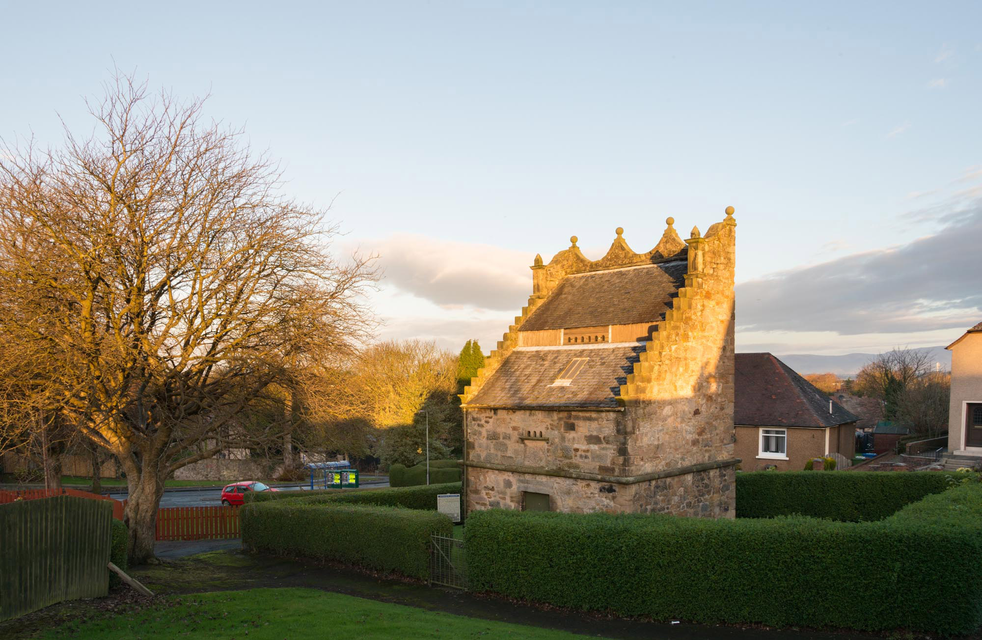 The very complete Westquarter dovecot is surrounded by a hedge and trees.