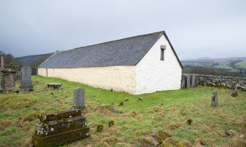 A white cottage-style church with a graveyard in front of it