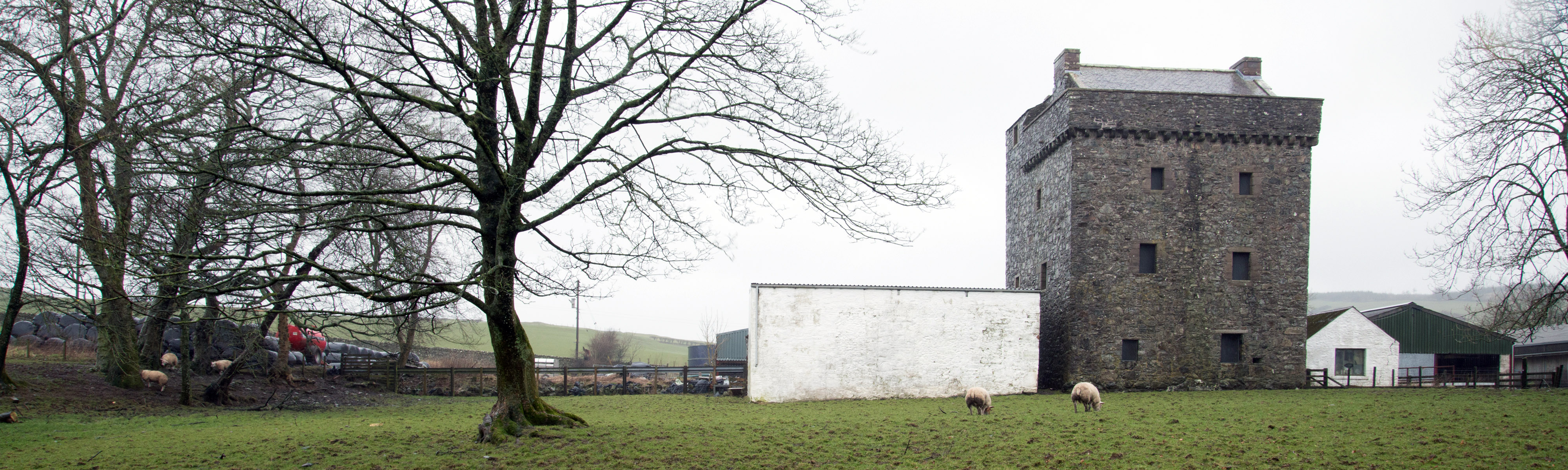 A dark square tower house surrounded by a few white modern buildings
