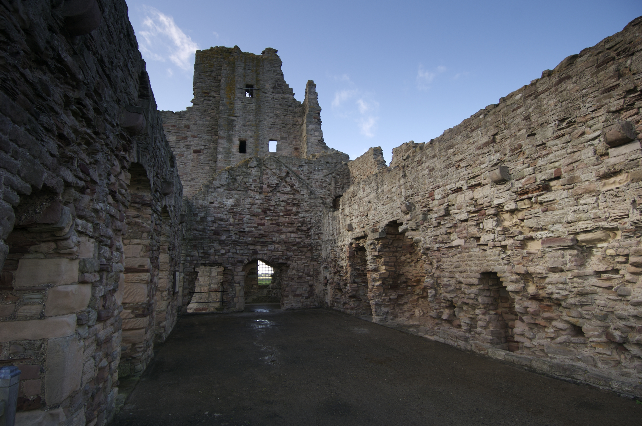 Interior view of large room in substantial castle ruin with blue sky visible 