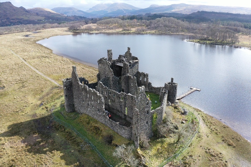 Aerial view of large ruined castle on the edge of a loch