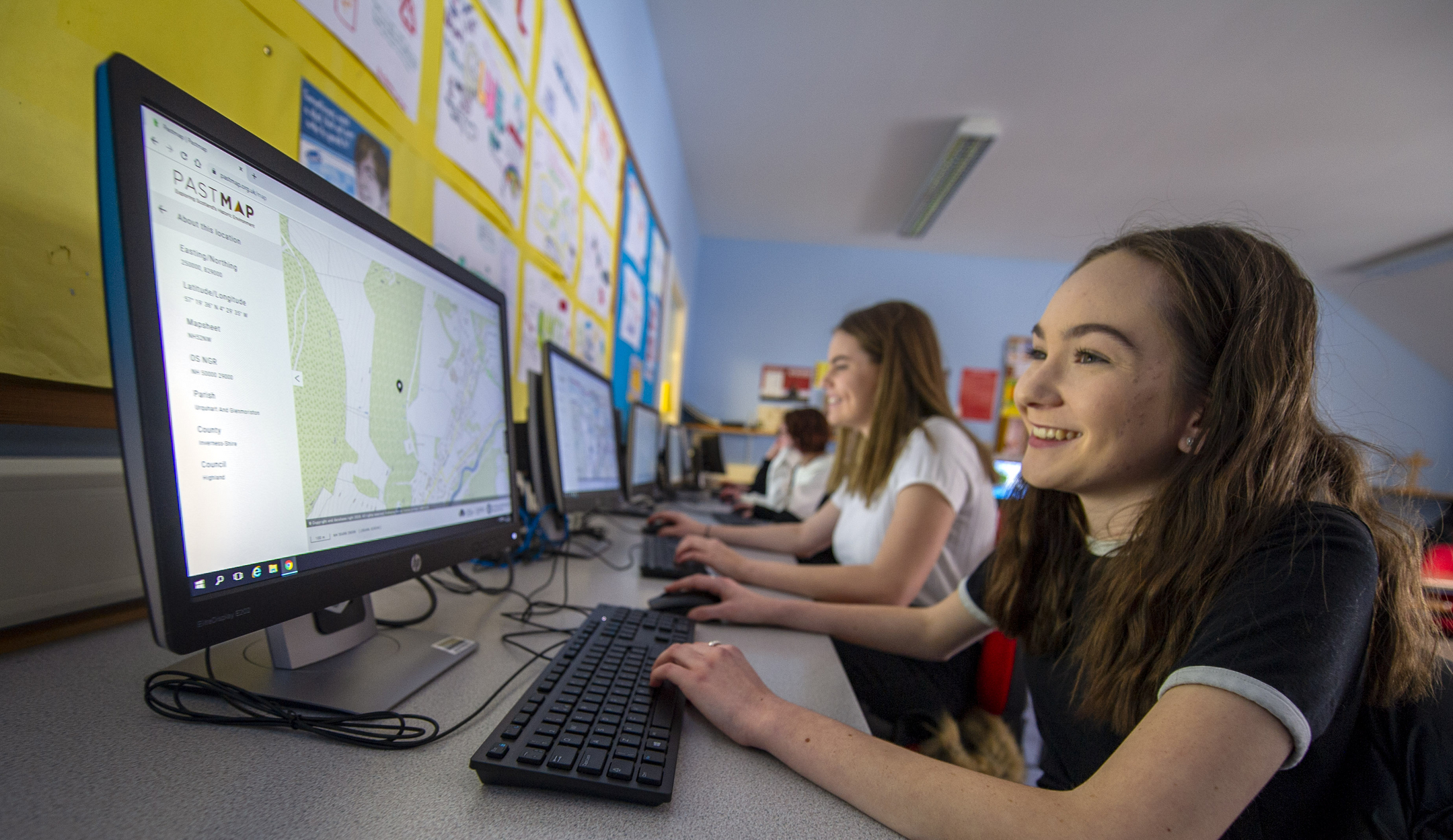 Two young women sat in a classroom looking at maps on the PASTMAP website.