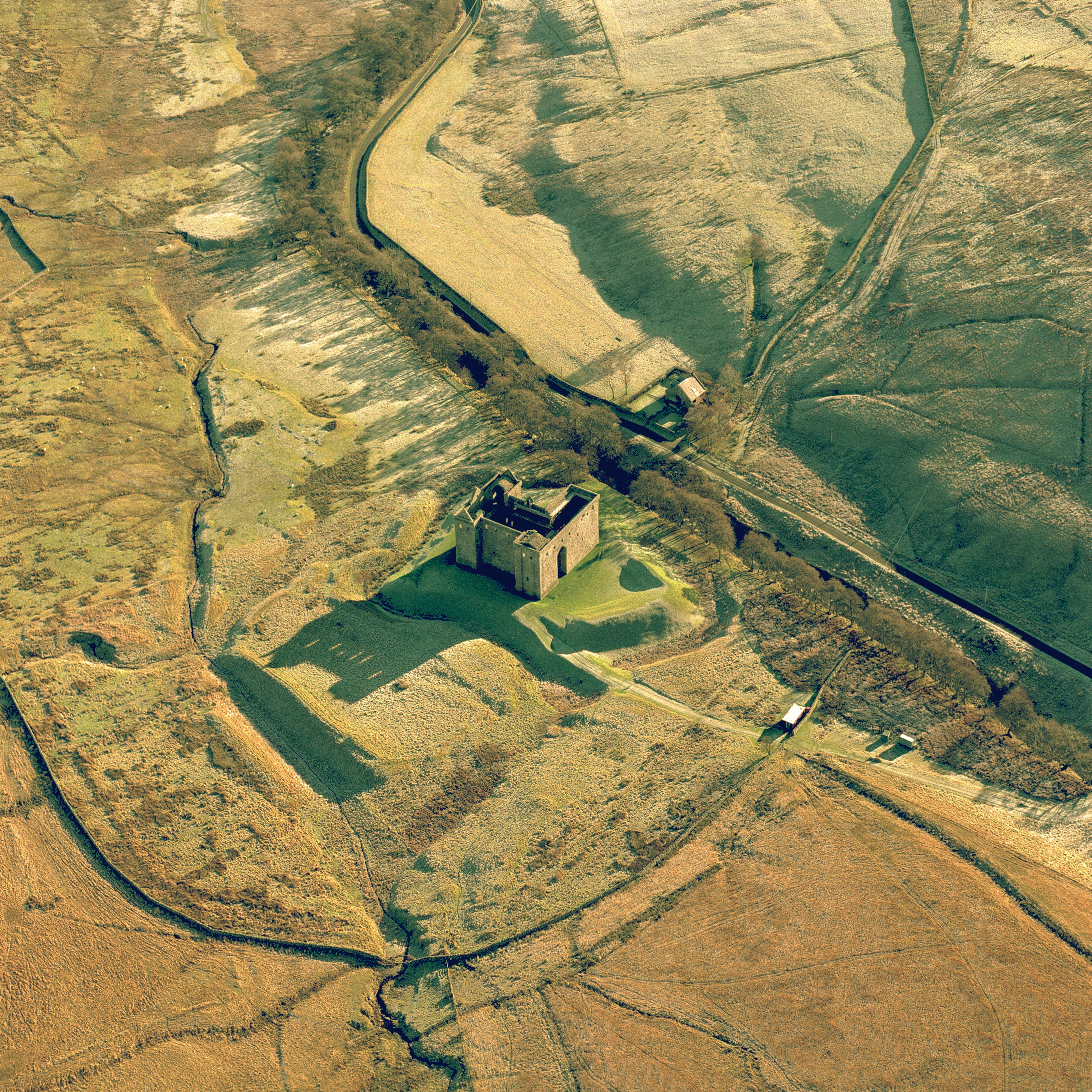 Aerial view of castle in the middle of the countryside on a sunny day with big shadows