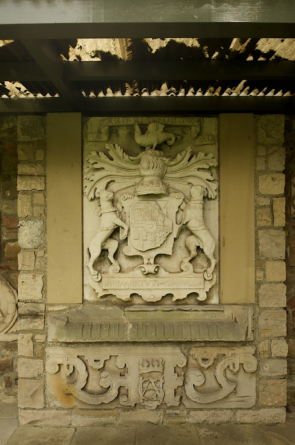 A stone panel, with stone brick around the outside. In the centre, there is a heraldic carving in the centre. 
