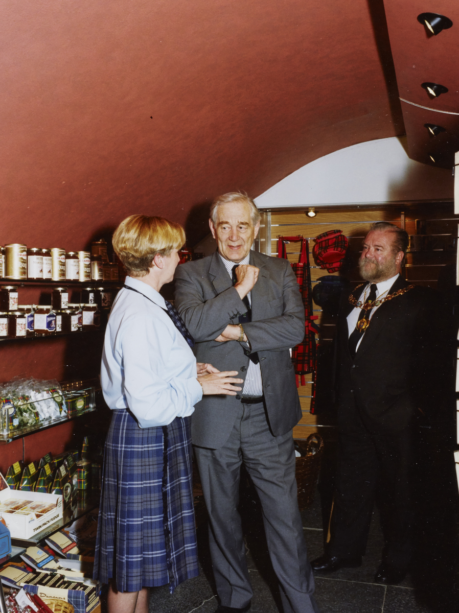 People conversing in a small shop with arched red ceiling