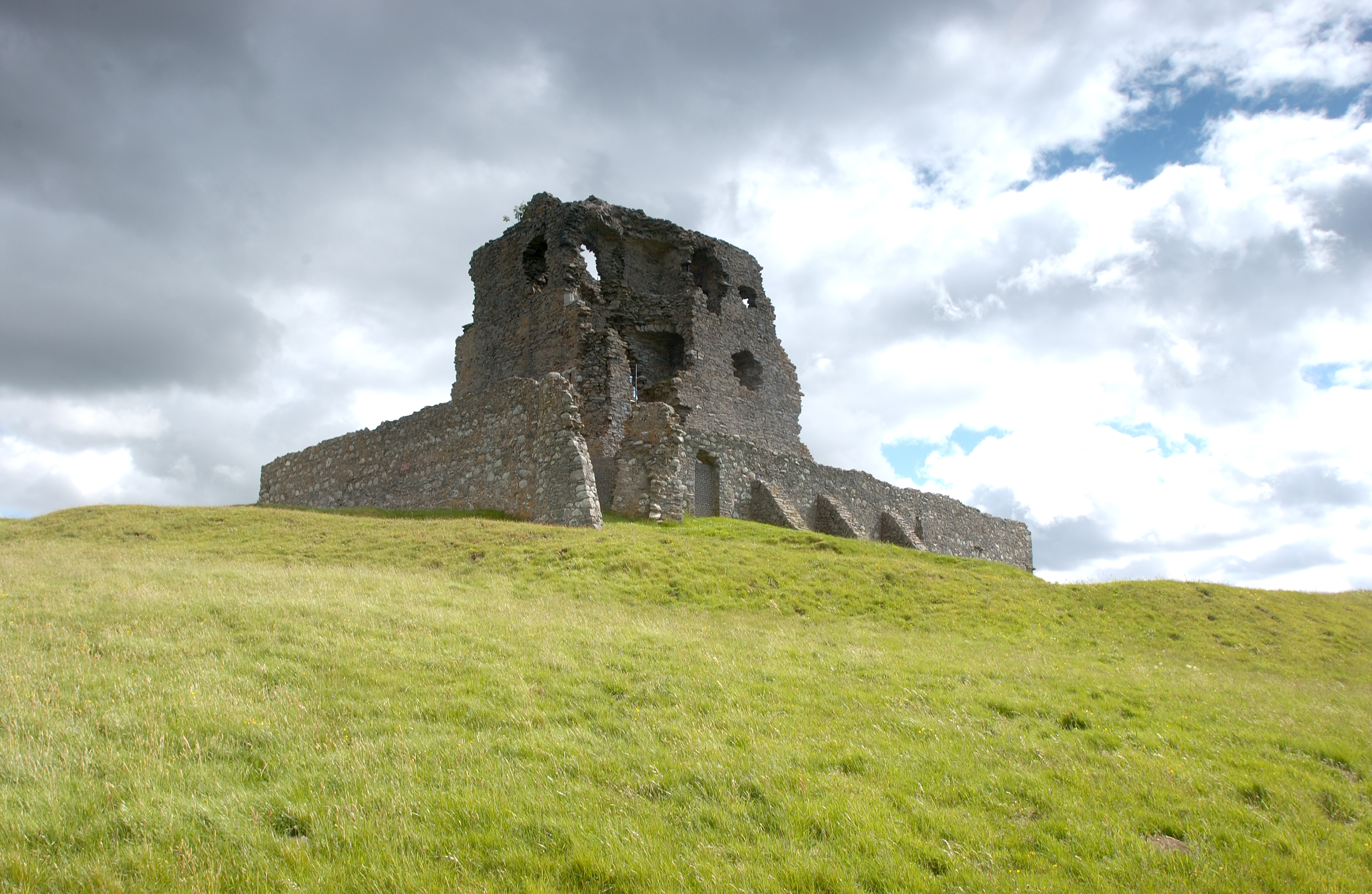 The imposing ruin of Auchindoun Castle in front of a dramatic and cloudy sky
