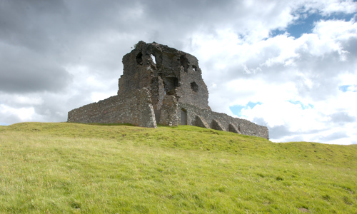 The imposing ruin of Auchindoun Castle in front of a dramatic and cloudy sky