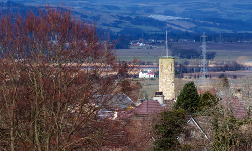 A light brown round tower is peeking out over the roofs of Abernethy