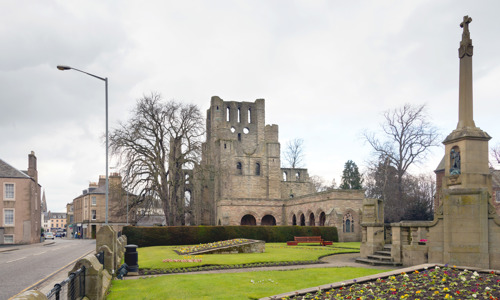 The ruins of Kelso Abbey next to a road and behind a cemetery