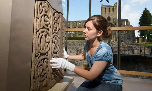 A staff member works to preserve a piece of sculptured stone.