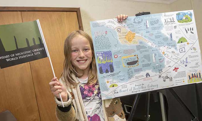 Primary school pupil holding Heart of Neolithic Orkney map and flag