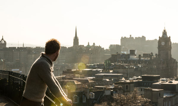 Man admiring the view of Edinburgh from Calton Hill in the sunshine